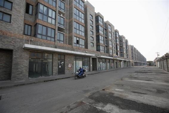 A worker rides a motorcycle on an empty street at the Rongsheng community in Nantong, Jiangsu province December 4, 2013. REUTERS-Aly Song