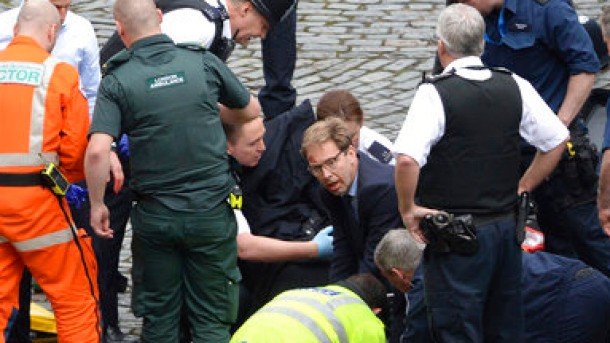 Conservative Member of Parliament Tobias Ellwood, centre, helps emergency services attend to an injured person outside the Houses of Parliament, London.