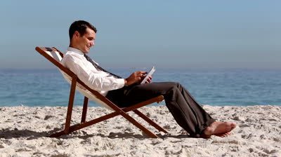 http://ak.picdn.net/shutterstock/videos/4877999/preview/stock-footage-smiling-businessman-using-tablet-and-relaxing-on-the-beach-on-the-sand.jpg
