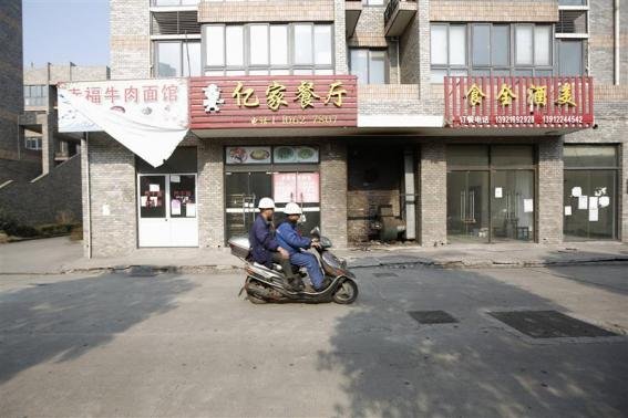 Workers ride a motorcycle past closed restaurants at the Rongsheng community in Nantong, Jiangsu province December 4, 2013. REUTERS-Aly Song